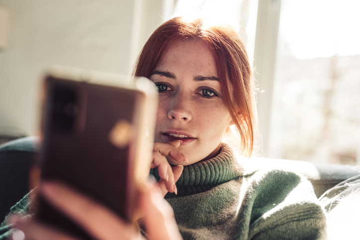 Young woman scrolling through social posts on her mobile phone